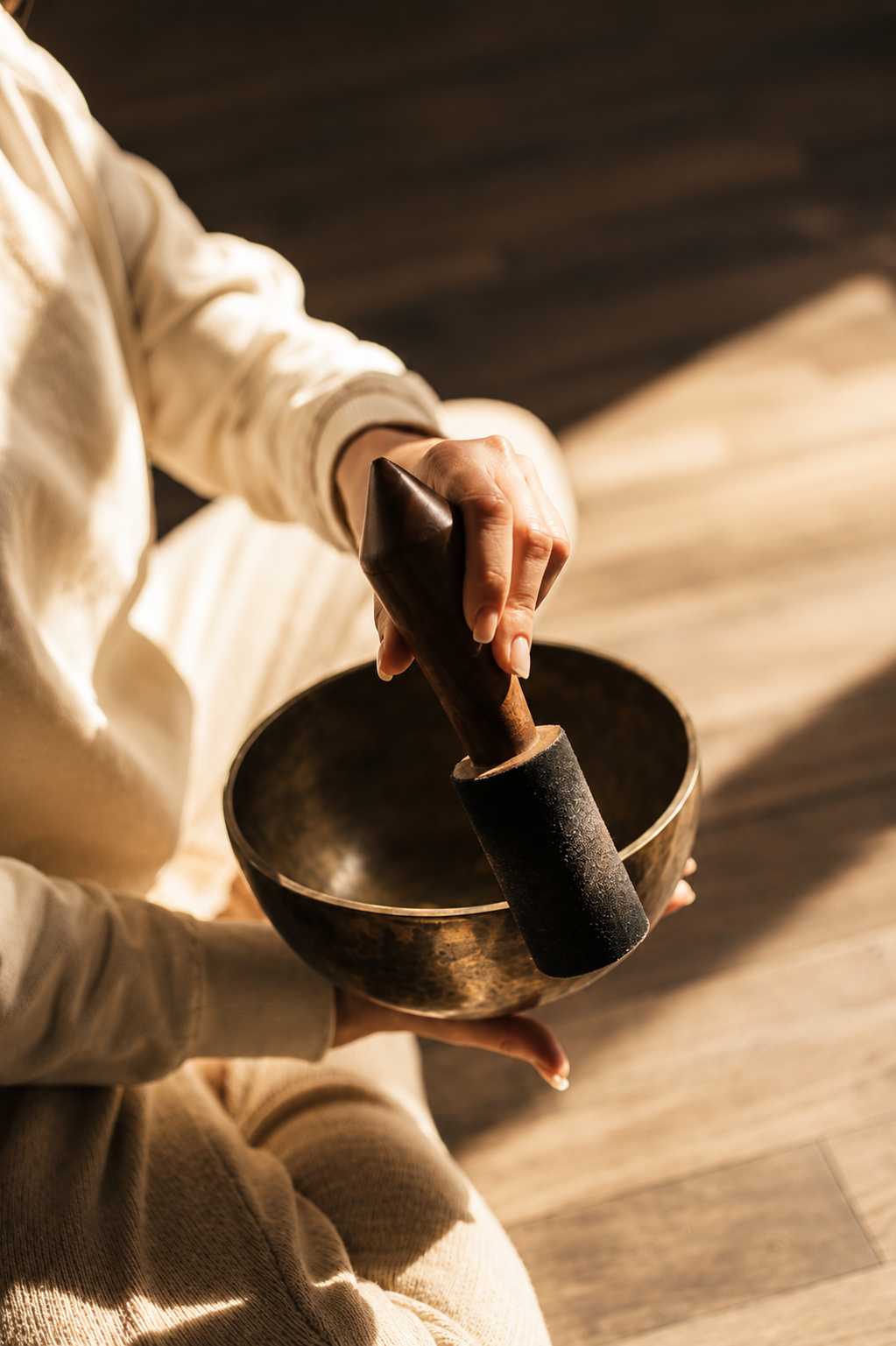 Hands playing bronze and crystal singing bowls during a sound healing session